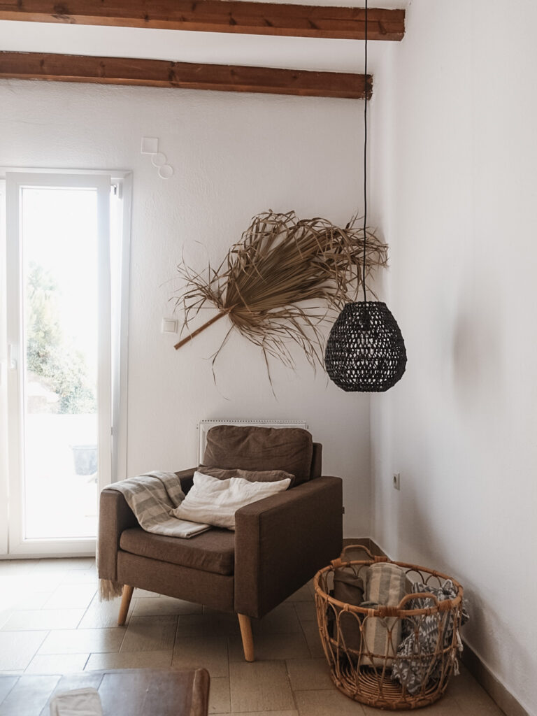 brown chair with dried palm leaf on wall